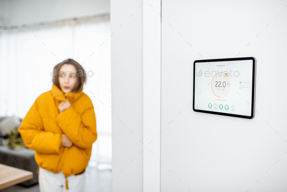 Smart home digital panel with heating app and woman feeling cold