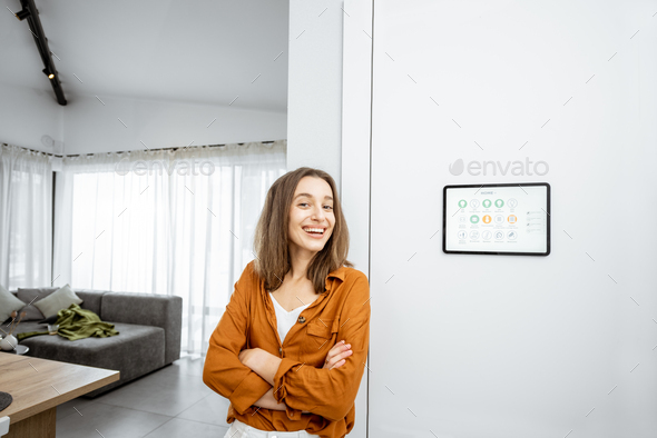 Portrait of a happy woman controlling home with a digital tablet