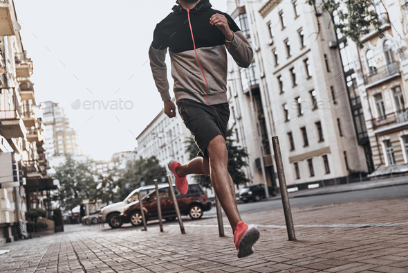 On the way to great shape. Close up of young man in sport clothing running along the city street