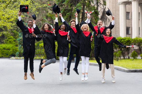 Happy students celebrating graduation from university, jumping up