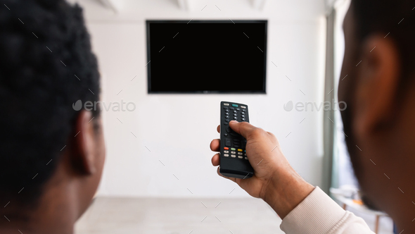 Black couple watching TV and using remote controller