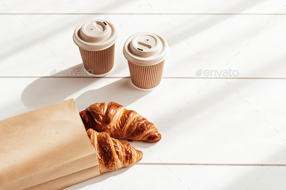 Hot coffee on the go and croissants for breakfast. Biodegradable, disposable takeaway cups