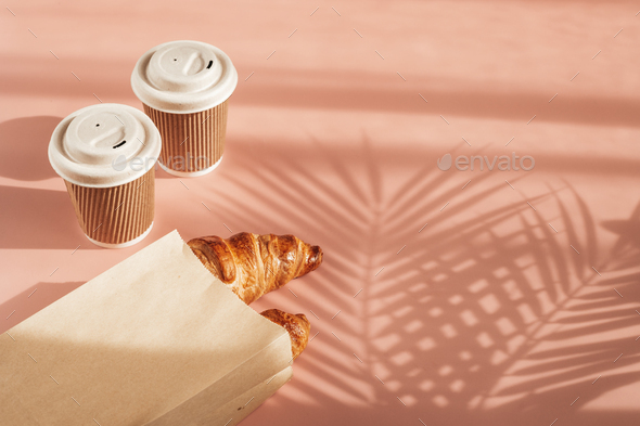 Hot coffee on the go and croissants for breakfast. Biodegradable, disposable takeaway cups