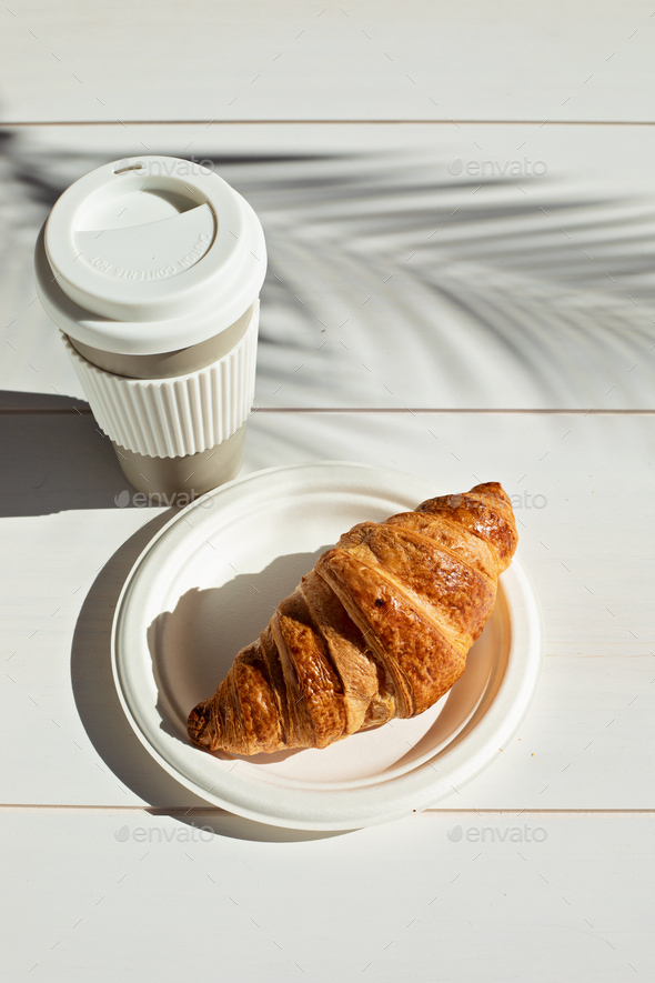 Hot coffee on the go and croissants for breakfast. Biodegradable, reusable takeaway cup