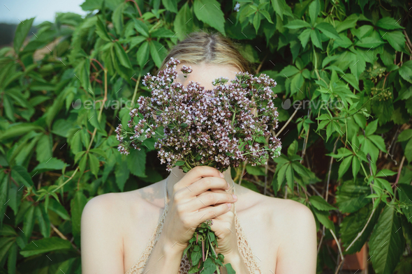 woman hold fresh cutting oregano plant bouquet and and hide face