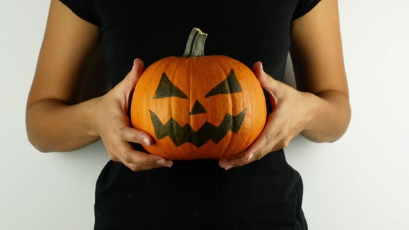 Halloween decorations and holidays - close-up of a woman holding a carved pumpkin in her hands