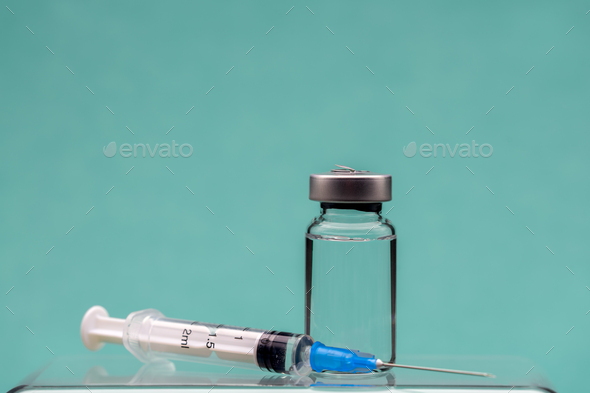Syringe on top on a vaccine bottle, green background. - Stock Photo - Images