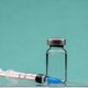 Syringe on top on a vaccine bottle, green background. - PhotoDune Item for Sale