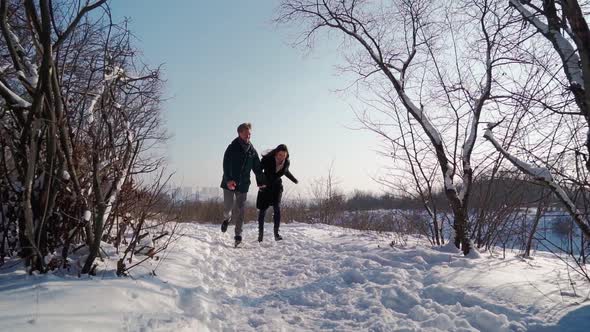 Happy Couple Running in Winter Forest alt