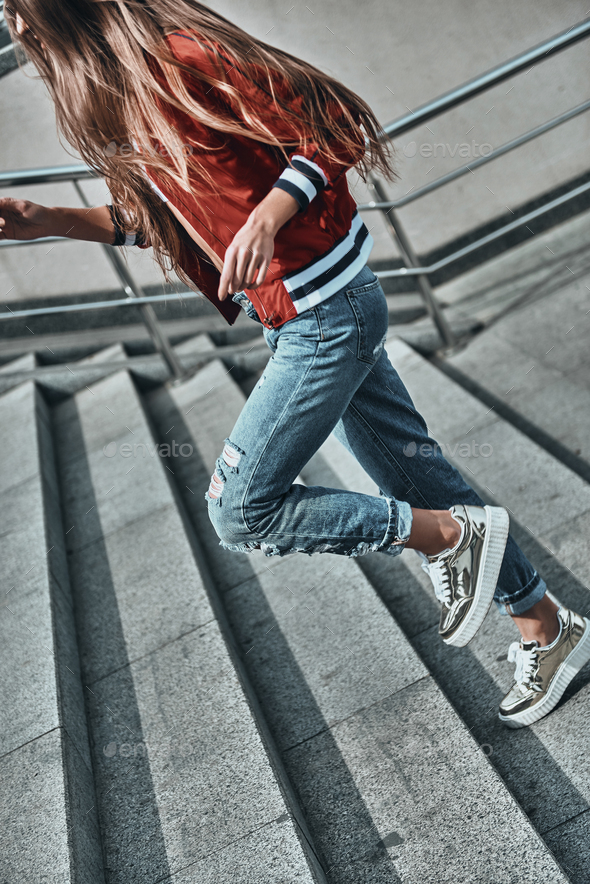 Choosing the right direction. Close-up of young woman in casual wear running up the stairs outdoors