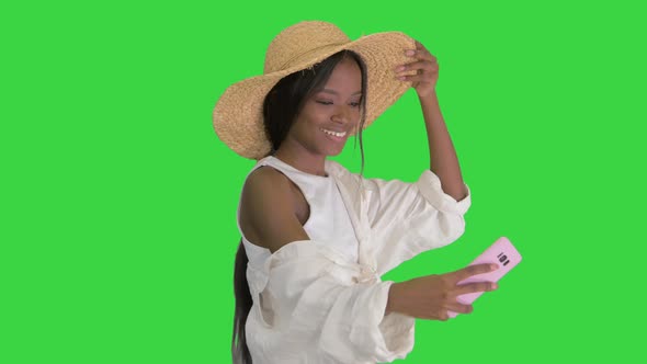 Smiling African American Woman in a Straw Hat Taking Selfie While Walking on a Green Screen, Chroma alt