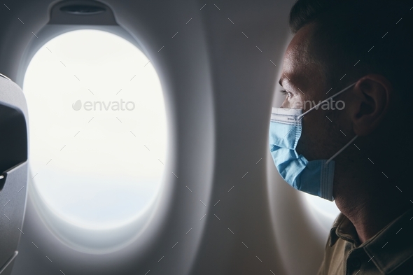 Man wearing face mask inside airplane during flight - Stock Photo - Images
