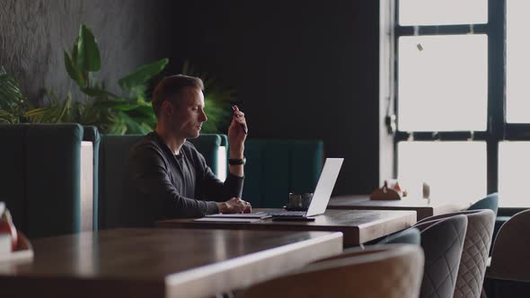Thoughtful Serious Young Man Student Writer Sit at Home Office Desk with Laptop Thinking of alt