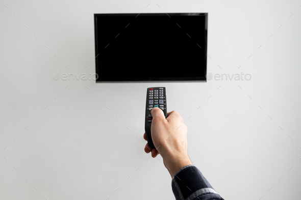 Hand Pointing Controller At Blank TV Screen On Wall Indoor