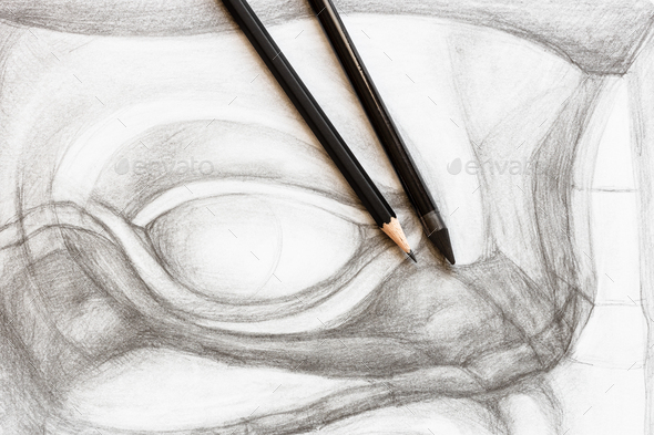 two graphite pencils on drawing of male eye