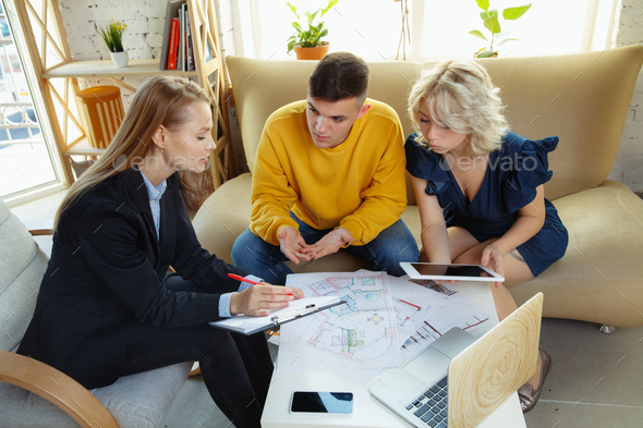 Interior designer working with young couple. Lovely family and professional designer or architector - Stock Photo - Images