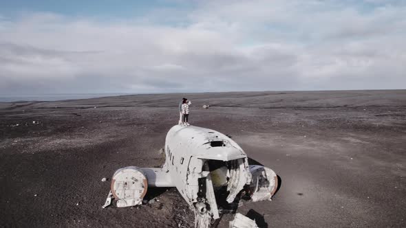 Aerial Shot of Travelers on Top of a Plane Wreck and Cloudy Skies in Backdrop alt