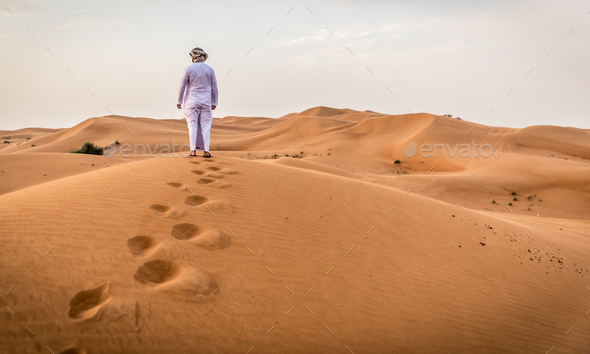 Middle eastern man wearing traditional clothes on desert dune