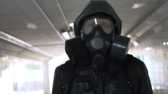 Man in Gas Mask Black Jacket with Hood Walking Through Long Tunnel Underpass alt