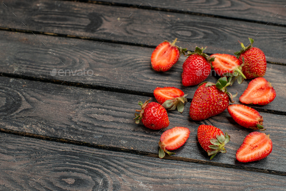 front view fresh red strawberries sliced and whole fruits on dark wooden rustic desk summer color