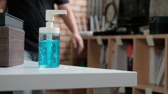 Casual man is pressing a bottle of alcohol gel and hand cleaning. alt