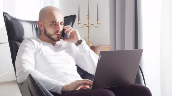 Bearded businessman working at home sitting in armchair. Business and investments concepts. alt