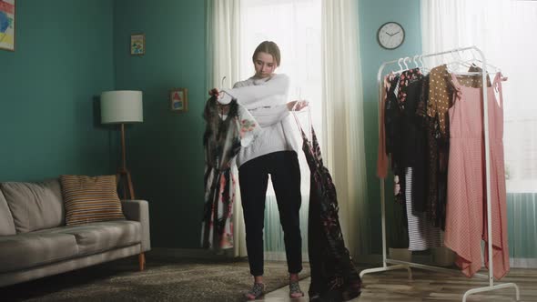 Young girl in a white sweater scatters clothes around the room