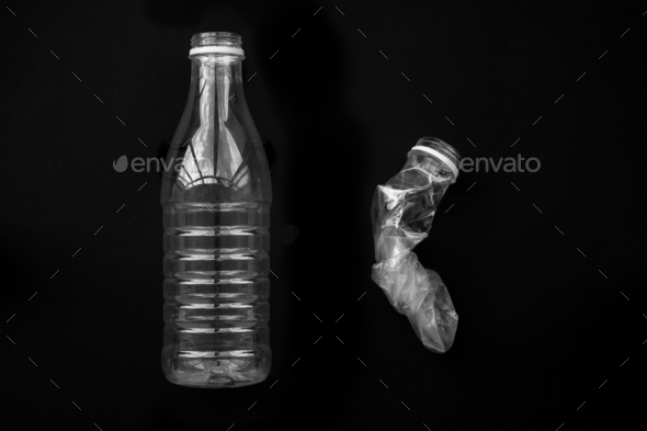 A squeezed and whole plastic bottle on a black background. The concept of saving the environment.