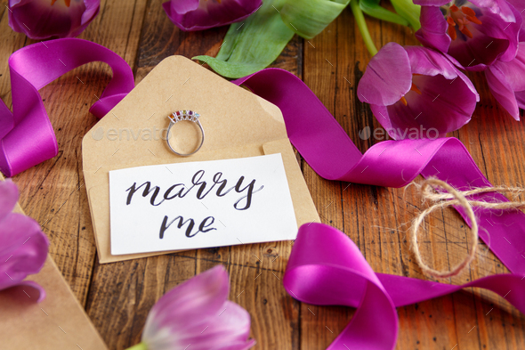 Purple tulips and MARRY ME card on wooden table