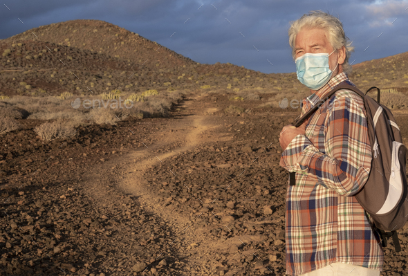 Elderly man walking in a path in an arid landscape enjoying nature. Cloudy sky and mountains - Stock Photo - Images