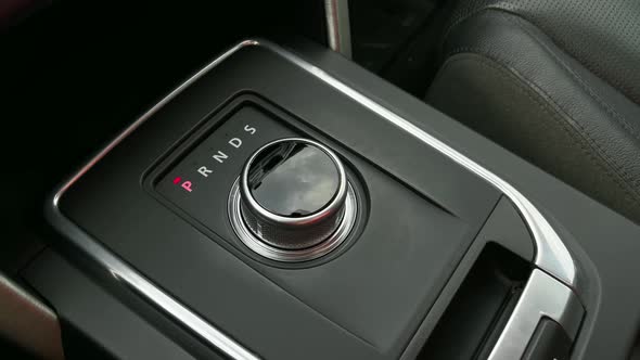 The man's hand switches gears in the car. Modern automatic transmission in the form of a washer