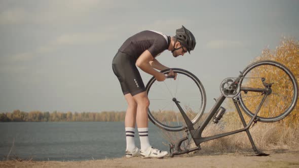 Cyclist Checking His Bike After Triathlon. Triathlete Fixes His Bicycle After Breakdown. alt