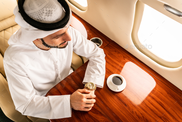 Arabian man wearing kandora flying on private jet - Stock Photo - Images