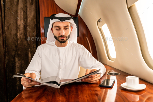 Arabian man wearing kandora flying on private jet - Stock Photo - Images