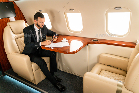 Businessman flying on private jet - Stock Photo - Images