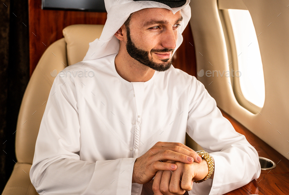 Arabian man wearing kandora flying on private jet - Stock Photo - Images