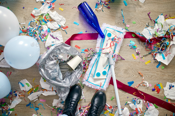 Woman with pushbroom cleaning mess of floor in room after party confetti