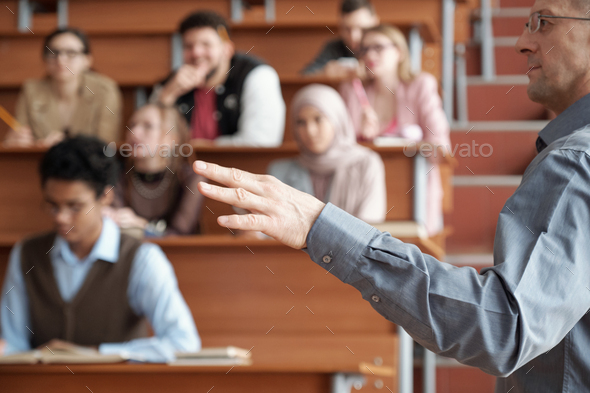Hand of professor in casualwear standing in front of audience and explaining subject of lecture