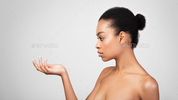 Serious African Lady Looking At Invisible Product In Hand, Studio - Stock Photo - Images