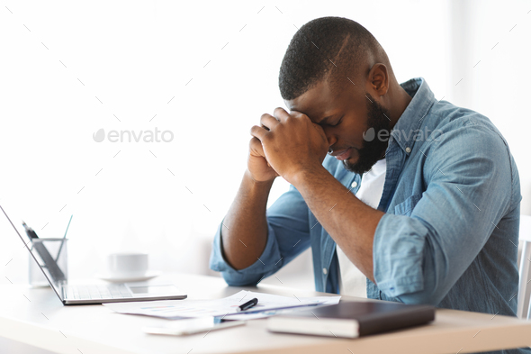 Crisis At Work. Depressed Black Businessman Sitting At Desk In Office