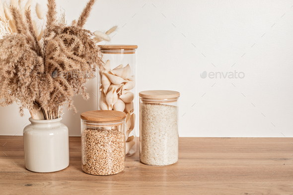 Assortment of grains, cereals and pasta in glass jars on wooden