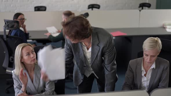 Portrait of Furious Dissatisfied Male CEO Passing Paperwork to Female Employees Leaving As Stressed alt