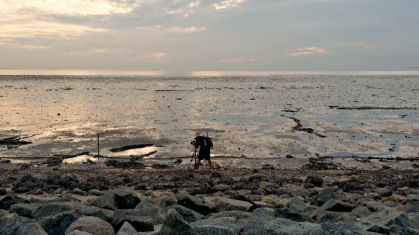 Silhouette asian cameraman photography low tide beach with sunset over sea on beach alt