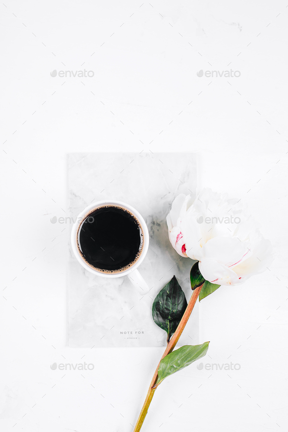 Coffee mug, notebook and white peony flowers on pink table background. Cozy, still life, minimal