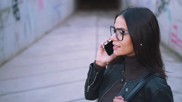 Young Stylish Woman in Glasses Talking on Phone Outdoors alt