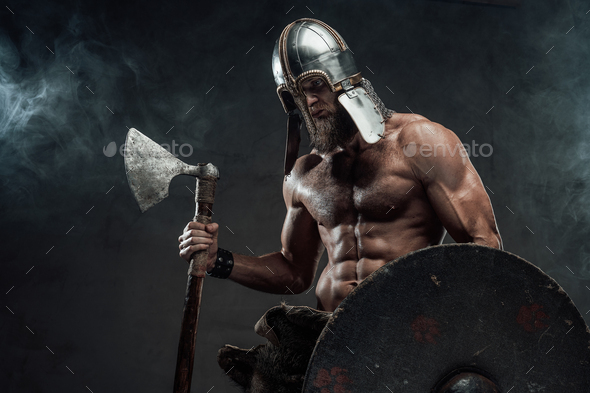 Armoured and naked viking posing with axe and shield in smoke