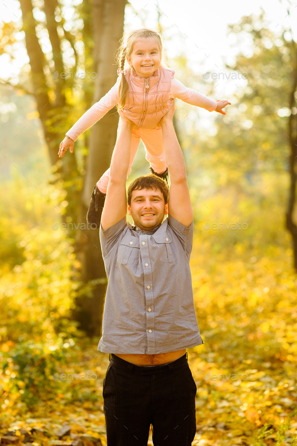 Father and daughter have fun together. Dad holds his daughter over his head.