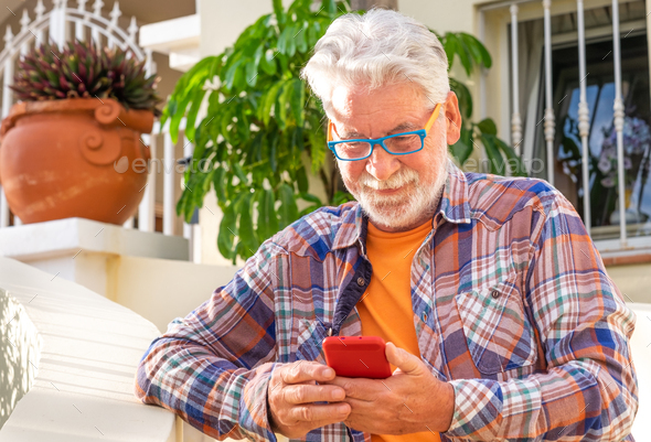 Portrait of senior man using technology with his smartphone. A white-haired old people out home