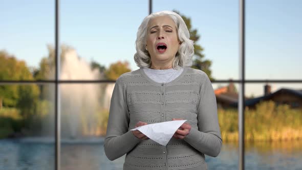 Mature Woman Sneezing or Blowing Nose. alt