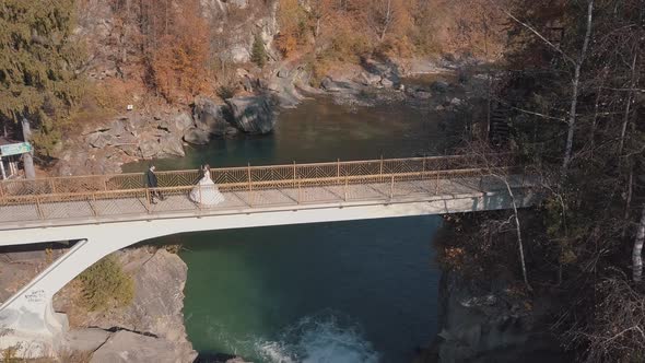 Newlyweds. Bride and Groom on a Bridge Over a Mountain River. Aerial View alt